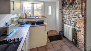 Une cuisine de taille réduite, avec une fenêtre, un mur en pierre et un radiateur.