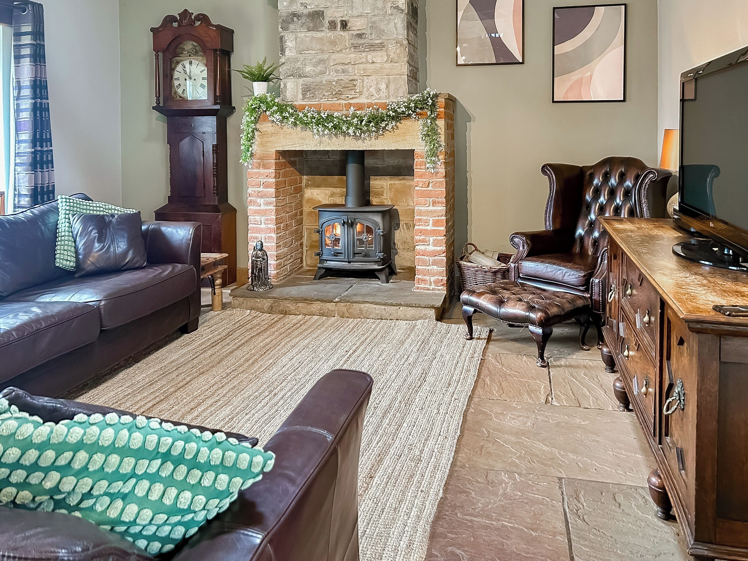 A cozy living room with a fireplace, leather furniture, and a clock on the wall.
