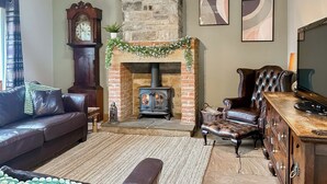 Una sala de estar acogedora con chimenea, muebles de cuero y un reloj en la pared.