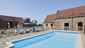 A swimming pool with lounge chairs and a wooden deck. - Archway Barn - E3864 (Runcton Holme)