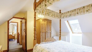 A bedroom with a four-poster bed, wooden wardrobe, and a skylight. - Archway Barn - E3864 (Runcton Holme)