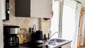 Una cucina compatta con macchina da caffè, bollitore e lavandino.