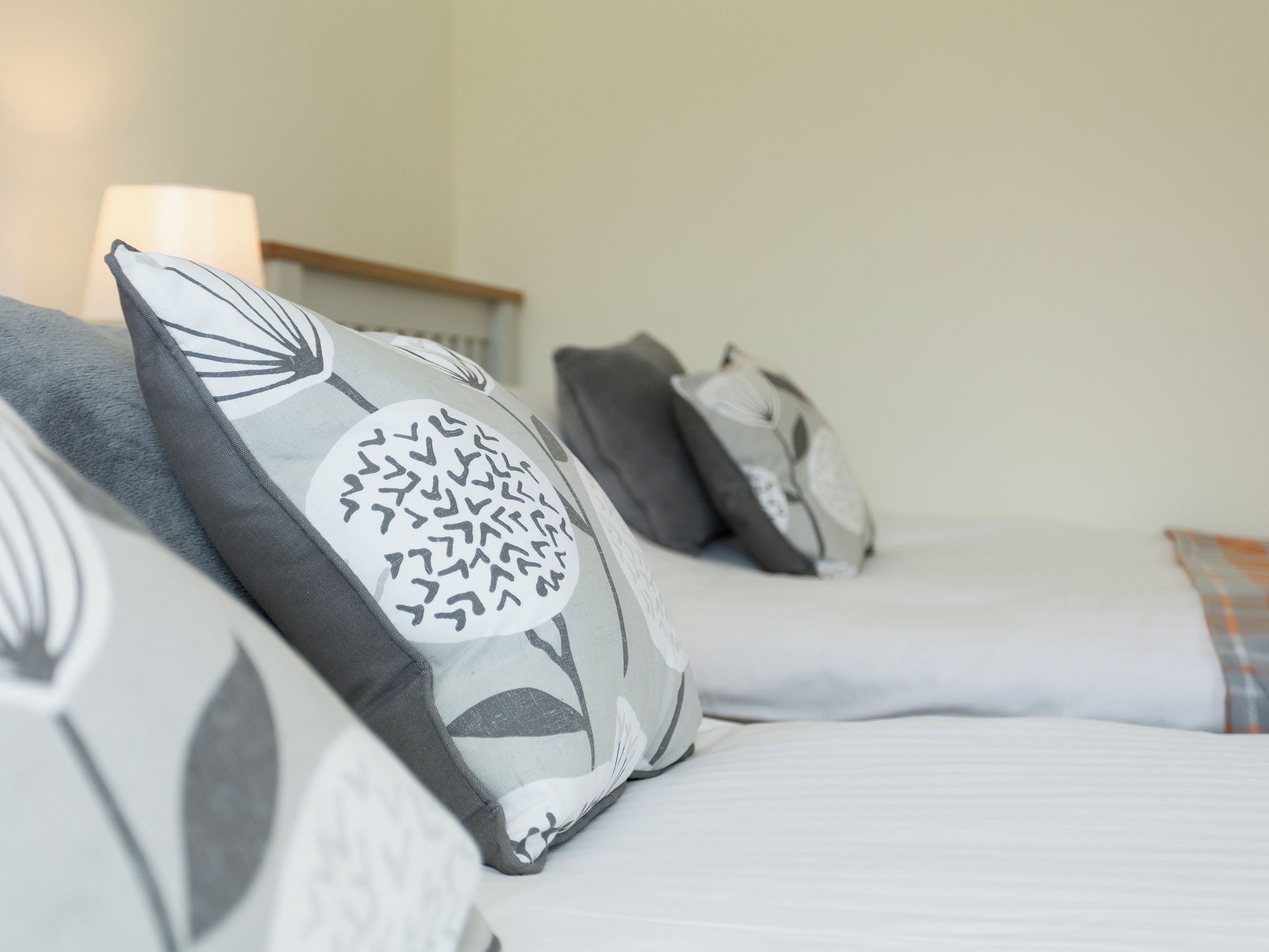 A bed with multiple pillows, a bedside table, and a lamp.