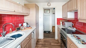 A kitchen with wooden cabinets, a sink, a stove, and a microwave. - 1 bedroom accommodation in North Stainmore, Kirkby Stephen (North Stainmore, Kirkby Stephen)
