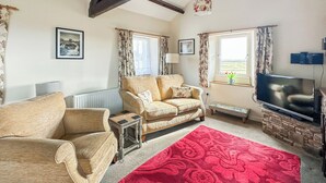 A living room with a sofa, armchair, TV, and a red patterned rug. - 1 bedroom accommodation in North Stainmore, Kirkby Stephen (North Stainmore, Kirkby Stephen)