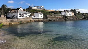 A coastal town with white buildings, a clear blue sky, and a calm sea. - Puffin Burrow, a beautiful historic couples retreat overlooking the Cove. (Portmellon, near Mevagissey)