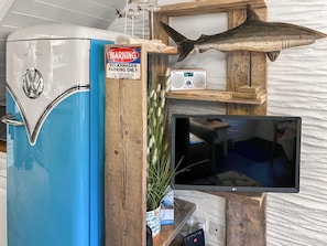 A vintage Volkswagen refrigerator, a warning sign, a radio, a television, and decorative items including a shark and antlers.