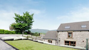A stone building with a sloped roof, a gravel driveway, and a grassy lawn. - 3 bedroom accommodation in Bradwell (Bradwell)