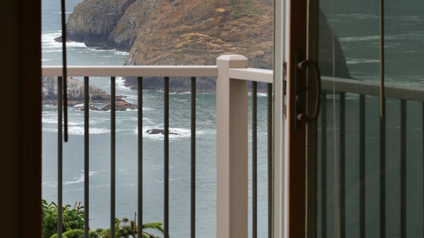 A view from a balcony overlooking a rocky coastline with the ocean. - Oceanside View House (Oceanside)