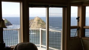 A room with a large window overlooking a rocky coastline and the sea. There is a tripod and a chair in the room. - Oceanside View House (Oceanside)