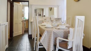 Un comedor con una mesa dispuesta para cuatro personas, sillas blancas y un reloj de pared.
