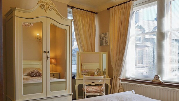 Un dormitorio con cama, cómoda, tocador y ventana con persianas.