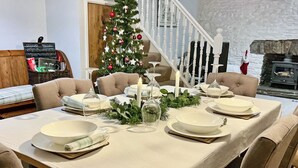 A dining table set with white plates and glasses, a Christmas tree, and a candle.