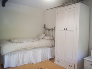 A bedroom with a bed, a wardrobe, and a dresser.