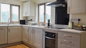 Una cucina moderna con mobili bianchi, un forno in acciaio inossidabile, un microonde e un tostapane.