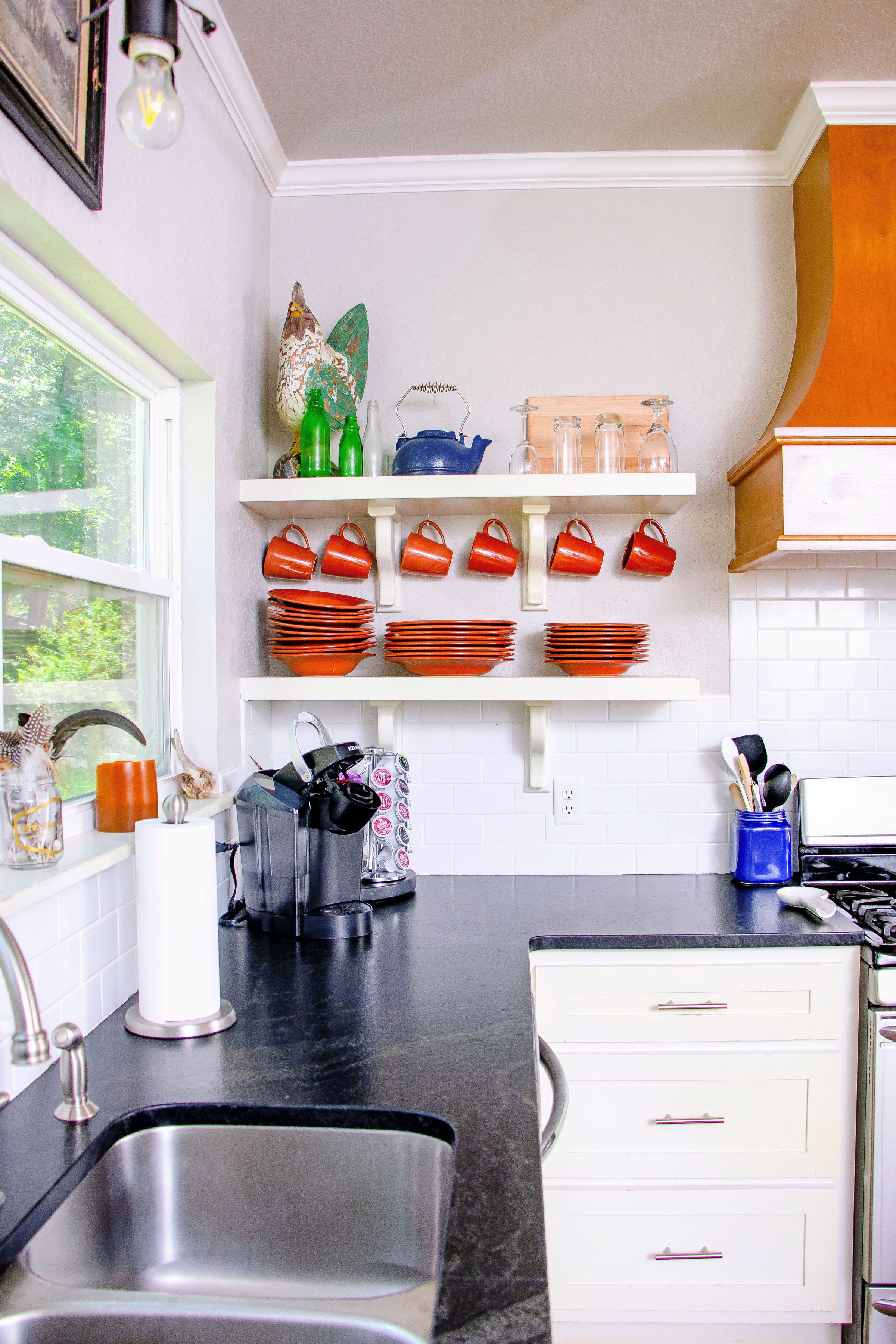A kitchen with a black countertop, white cabinets, and a stainless steel sink.