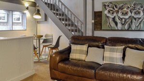 A brown leather sofa with plaid cushions, a glass-top coffee table, and a painting of owls on the wall. - 2 bedroom accommodation in Grasmere (Grasmere)