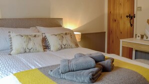 A bedroom with a bed, pillows, a bedside table, a lamp, and a wooden door. - 2 bedroom accommodation in Grasmere (Grasmere)