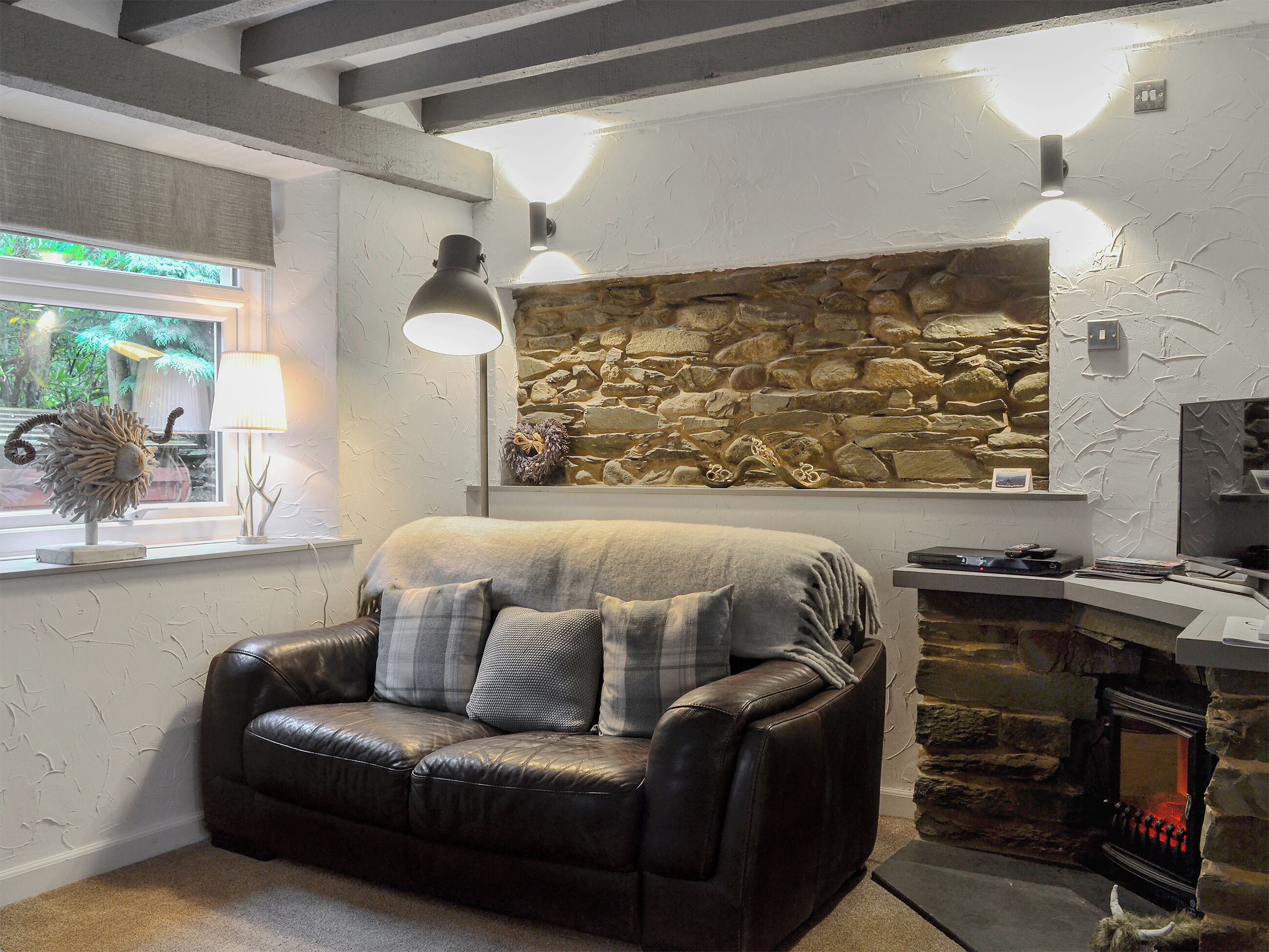 Ein gemütliches Wohnzimmer mit Kamin aus Stein, einer Ledersofa und einer Lampe.