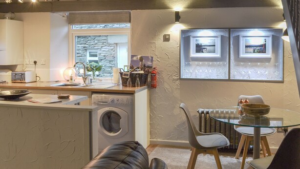 A kitchen with a washing machine, a dining table with chairs, and a radiator. - 2 bedroom accommodation in Grasmere (Grasmere)