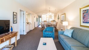 A living room with a sofa, a coffee table, a TV, and a dining area with chairs and a table. - TB 9I Super 3rd floor condo True Blue Golf/Tennis Accessible WINTER RENTAL (Pawleys Island)