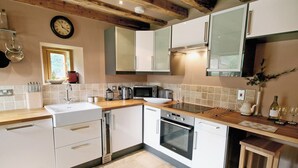 A modern kitchen with white cabinets, a wooden countertop, a built-in oven, and a coffee maker.