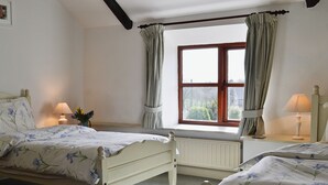 A bedroom with two single beds, a window with curtains, a radiator, and bedside lamps. - 2 bedroom accommodation in Altarnun, near Launceston (Altarnun, near Launceston)