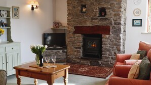 A cozy living room with a stone fireplace, a television, and a comfortable seating area. - 2 bedroom accommodation in Altarnun, near Launceston (Altarnun, near Launceston)