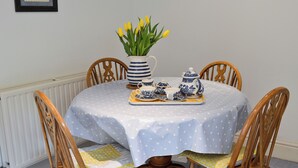 A round dining table with a polka dot tablecloth, surrounded by four wooden chairs with cushioned seats. A vase with yellow flowers is placed on the table. - 2 bedroom accommodation in Altarnun, near Launceston (Altarnun, near Launceston)