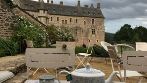 A table set for tea and cake with a view of a castle in the background.