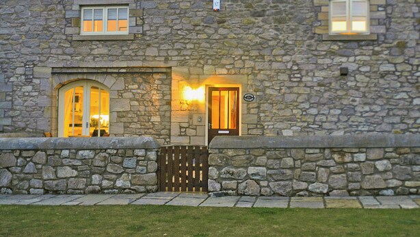 A stone building with two windows, a door, and a small sign above the door. - 3 bedroom accommodation in Steading, Berwick-upon-Tweed (Steading, Berwick-upon-Tweed)