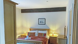 A bedroom with a wooden bed, bedside tables, a small wooden cabinet, and a framed picture on the wall. - 3 bedroom accommodation in Steading, Berwick-upon-Tweed (Steading, Berwick-upon-Tweed)