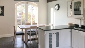A kitchen with white cabinets, a black countertop, and a dining area with a table and chairs. - 3 bedroom accommodation in Steading, Berwick-upon-Tweed (Steading, Berwick-upon-Tweed)