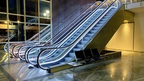 Een reeks roltrappen in een modern gebouw met een marmeren vloer en grote ramen.