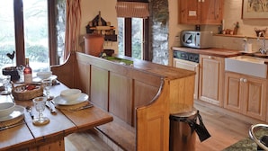 Una cucina rustica con mobili in legno, un muro in pietra e un'area pranzo con una panca.