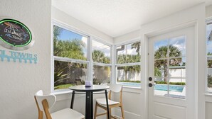 A corner room with a pool view, a small table, two chairs, and a door with a pool view. - SaltRunner: Updated 3/2 home with Private Pool (St. Augustine)