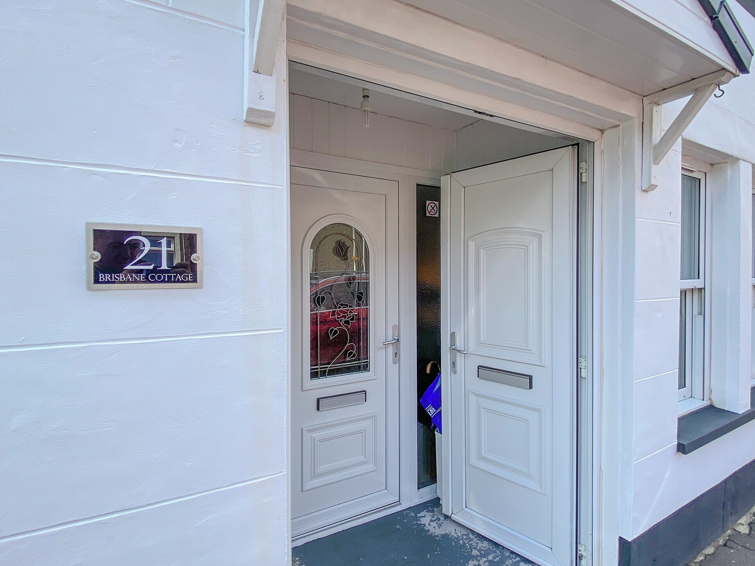 Una puerta blanca con un panel de vidrio y un letrero que dice "21 Brisbane Cottage".