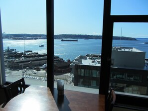 A view from a window overlooking a harbor with ships, a cityscape, and a distant island. - 1 Block to Pike Pl Market & Easy Walk to Stadium ~ Balcony with Water Views (Seattle)