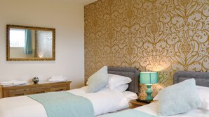Habitación de hotel con dos camas, una mesita de noche con lámpara, un aparador y un espejo en la pared.