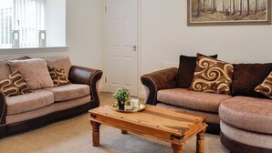 A living room with two brown sofas, a wooden coffee table, and a painting on the wall. - Kirroughtree Steading 1 - UK5859 (Newton Stewart)