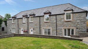 A stone building with multiple windows and a sloped roof. - Kirroughtree Steading 1 - UK5859 (Newton Stewart)