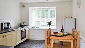 A kitchen with a window, a dining table with chairs, a toaster, and a refrigerator. - Kirroughtree Steading 1 - UK5859 (Newton Stewart)