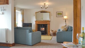 A living room with two sofas, a fireplace, a television, and a table with a magazine.