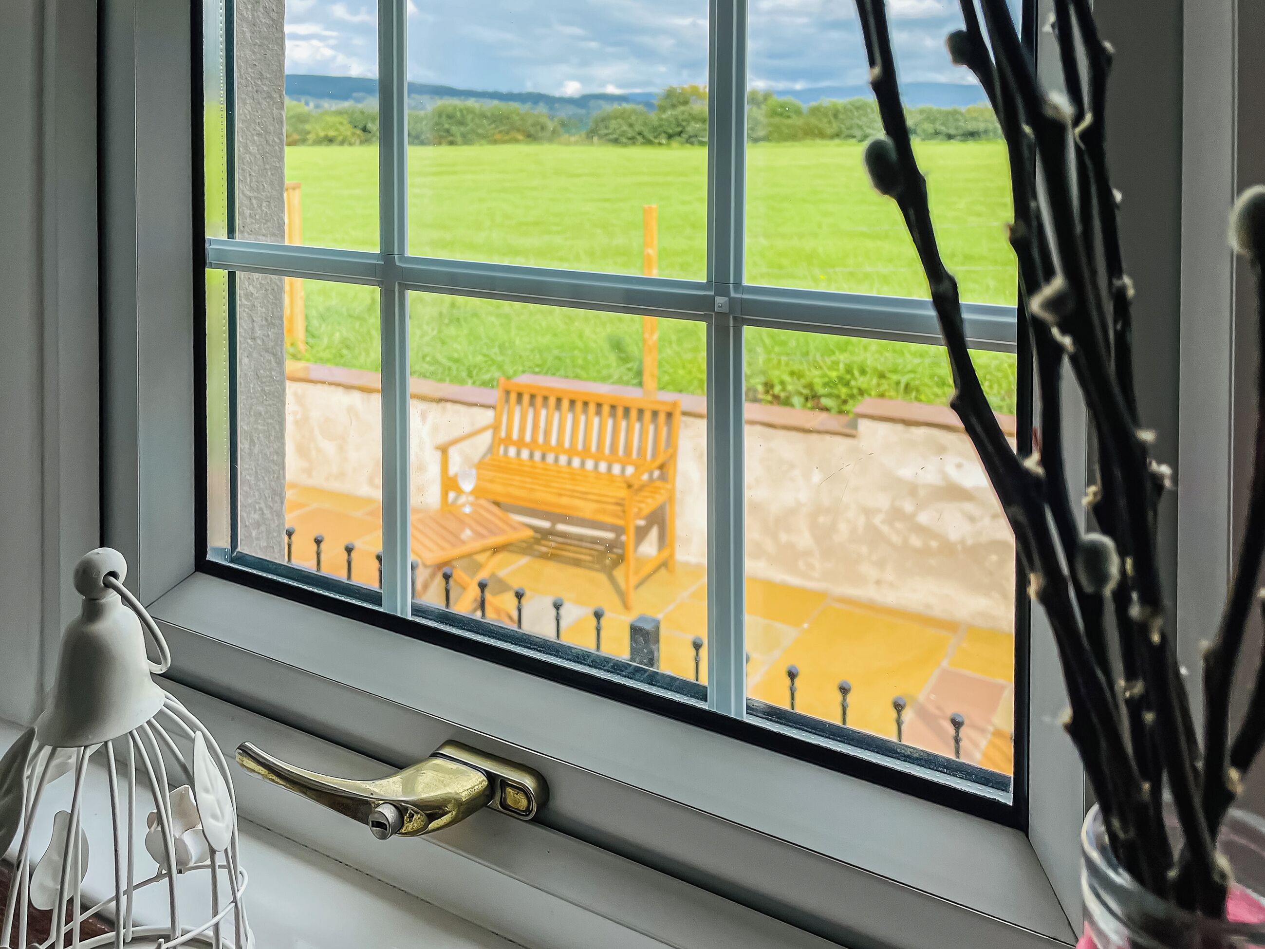 Ein Fenster mit Blick auf eine Terrasse, inklusive einer Bank und einem Geländer.