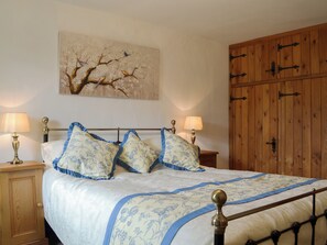 A bedroom with a bed, two bedside lamps, a wooden wardrobe, and a wall painting.