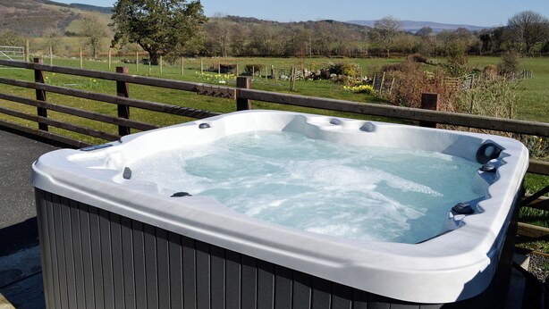 A hot tub with a wooden fence and a view of a rural landscape. - 4 bedroom accommodation in Rhyduchaf, near Bala (Rhyduchaf, near Bala)