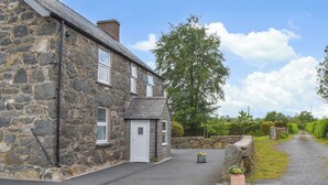 A stone building with a door, windows, and a small garden area with flowers. - 4 bedroom accommodation in Rhyduchaf, near Bala (Rhyduchaf, near Bala)