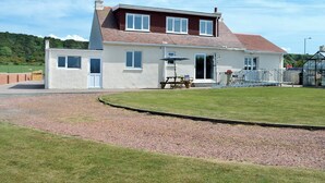 Une maison à deux étages avec un jardin, une terrasse et une allée gravillonnée.