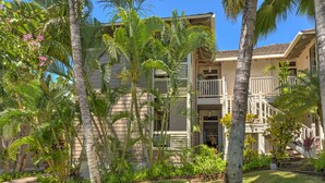 A two-story building with a balcony and a covered walkway. - Spacious End Unit (Kihei)