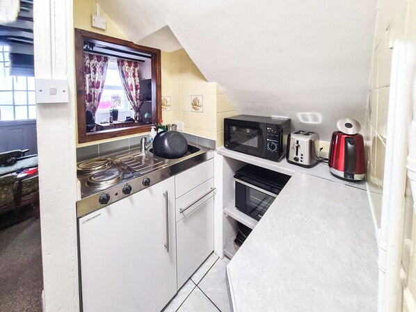 Una cucina compatta con piano cottura, forno a microonde, tostapane e forno.